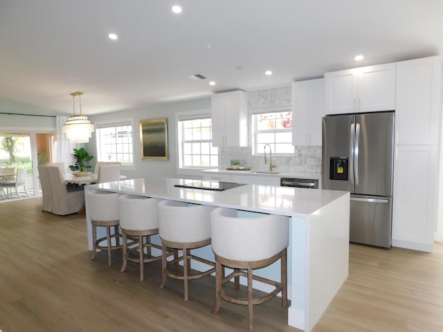 889 SW Balmoral Trce, Stuart, FL 34997 - kitchen featuring appliances with stainless steel finishes, a kitchen island, light countertops, white cabinetry, and plenty of natural light