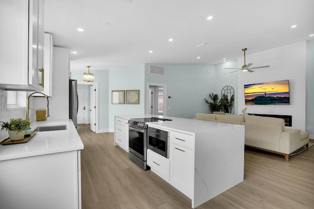 889 SW Balmoral Trce, Stuart, FL 34997 - kitchen with a sink, white cabinets, light wood-type flooring, stainless steel range with electric cooktop, and recessed lighting