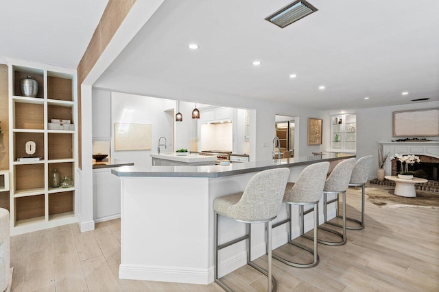 3356 NW 24th Way, Boca Raton, FL 33431 - kitchen featuring a large island with sink, white cabinetry, light wood-type flooring, a kitchen bar, and recessed lighting
