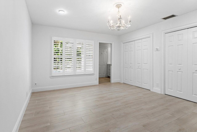 3356 NW 24th Way, Boca Raton, FL 33431 - unfurnished bedroom with multiple closets, a chandelier, and light wood-style flooring
