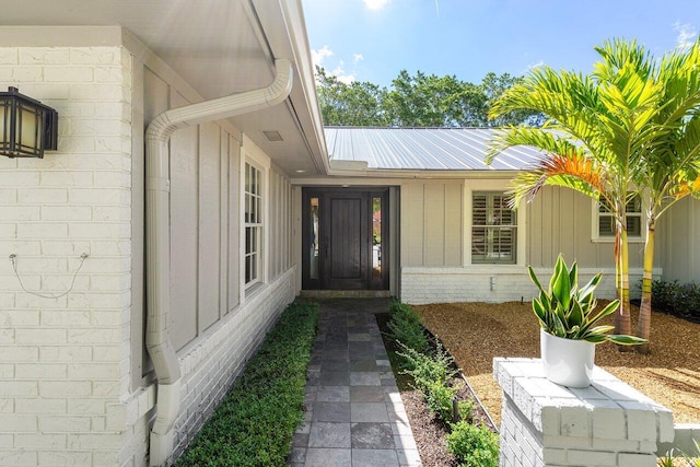 3356 NW 24th Way, Boca Raton, FL 33431 - view of exterior entry featuring board and batten siding, a metal roof, and brick siding