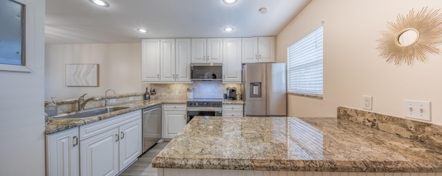 1428 S Lakeside Dr Unit 31, Lake Worth Beach, FL 33460 - kitchen featuring stainless steel appliances, a sink, a peninsula, white cabinets, and decorative backsplash