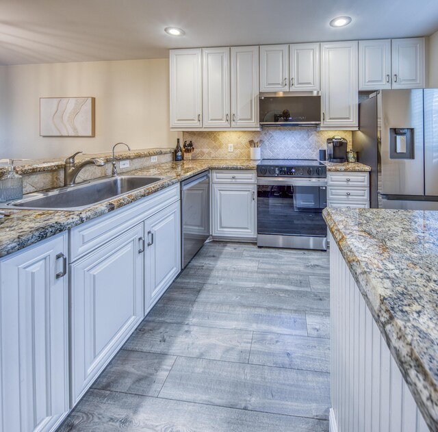 1428 S Lakeside Dr Unit 31, Lake Worth Beach, FL 33460 - kitchen with appliances with stainless steel finishes, a sink, light wood-type flooring, white cabinets, and light stone counters