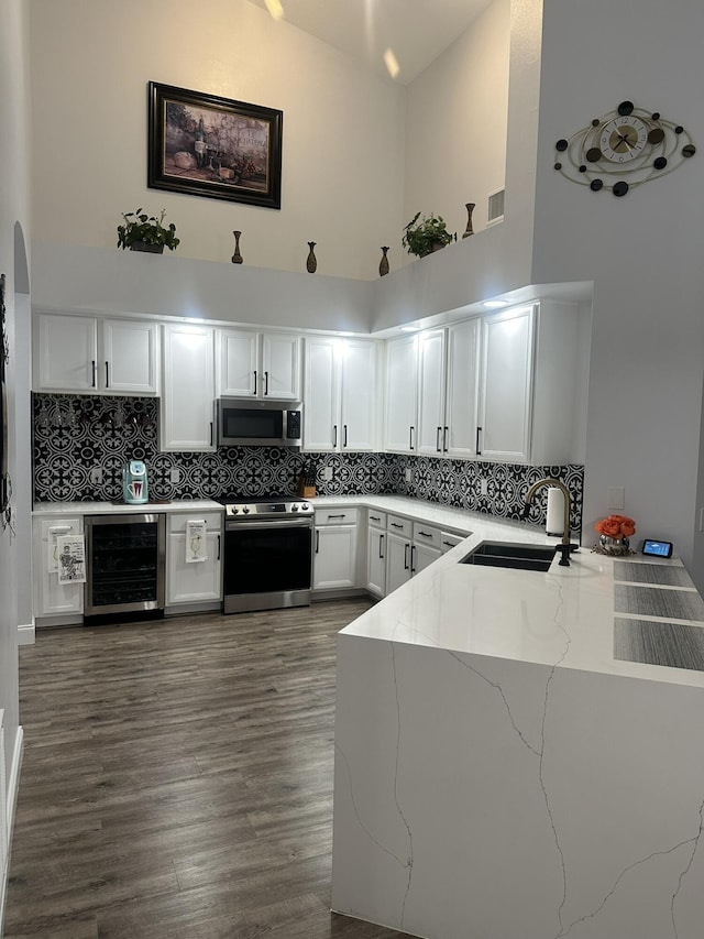 1583 SW Harbour Isles Cir Unit 57, Port Saint Lucie, FL 34986 - kitchen with appliances with stainless steel finishes, wine cooler, a sink, high vaulted ceiling, and light stone countertops