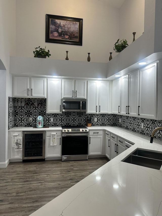1583 SW Harbour Isles Cir Unit 57, Port Saint Lucie, FL 34986 - kitchen with appliances with stainless steel finishes, wine cooler, a sink, white cabinetry, and tasteful backsplash