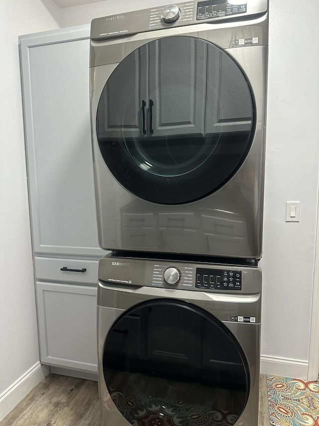 1583 SW Harbour Isles Cir Unit 57, Port Saint Lucie, FL 34986 - laundry area with stacked washer / dryer, baseboards, light wood-style flooring, and cabinet space