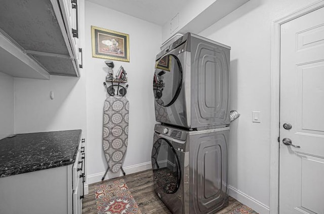1583 SW Harbour Isles Cir Unit 57, Port Saint Lucie, FL 34986 - washroom featuring estacked washer and dryer, cabinet space, dark wood-type flooring, and baseboards