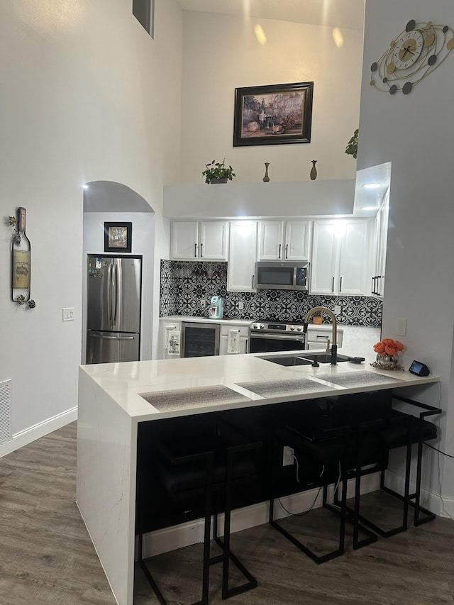 1583 SW Harbour Isles Cir Unit 57, Port Saint Lucie, FL 34986 - kitchen with appliances with stainless steel finishes, a high ceiling, wine cooler, a peninsula, and a kitchen breakfast bar