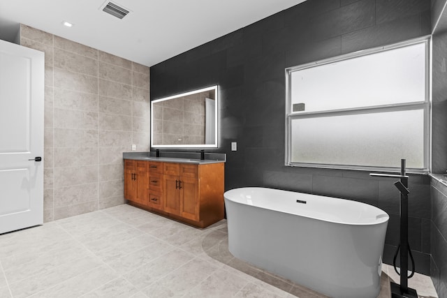 4037 SW Port St Lucie Blvd, Port Saint Lucie, FL 34953 - full bath with tile walls, double vanity, a freestanding bath, and tile patterned flooring
