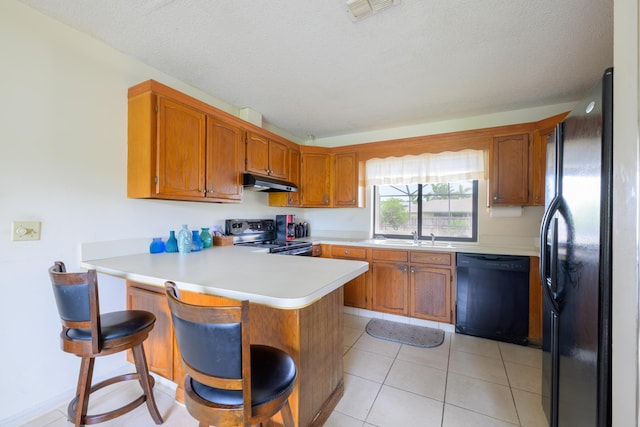 858 SE Roulette Ln, Port Saint Lucie, FL 34983 - kitchen with black appliances, under cabinet range hood, a peninsula, light countertops, and brown cabinetry
