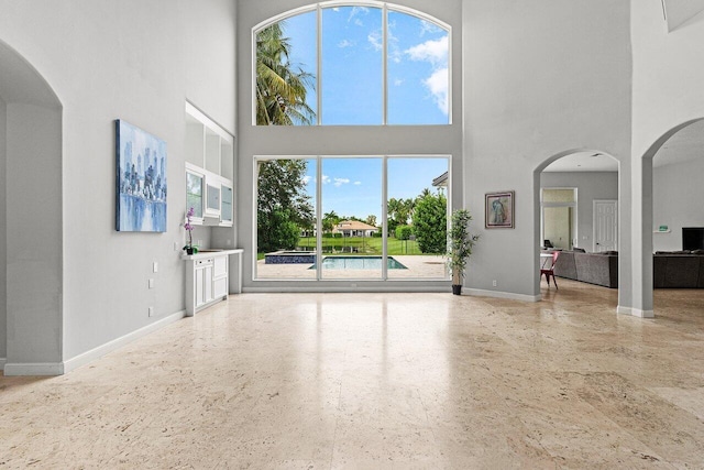 16370 Via Fontana, Delray Beach, FL 33484 - unfurnished living room featuring a high ceiling, plenty of natural light, baseboards, and arched walkways