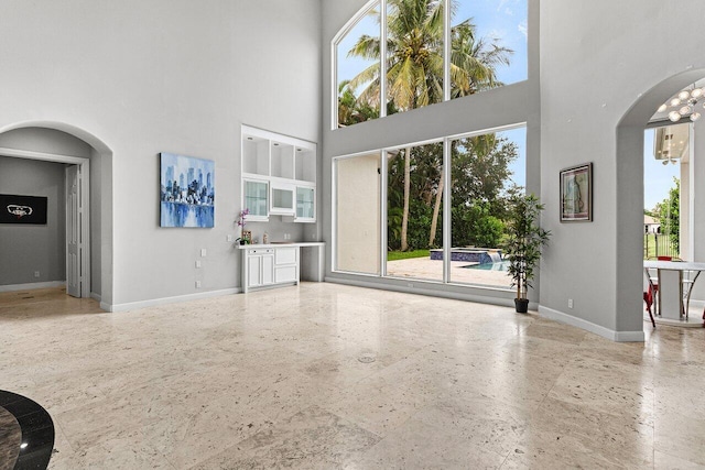 16370 Via Fontana, Delray Beach, FL 33484 - unfurnished living room with arched walkways, a high ceiling, and baseboards