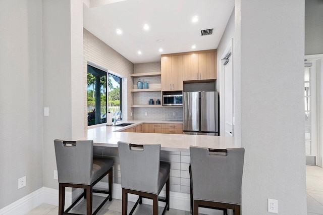 16370 Via Fontana, Delray Beach, FL 33484 - kitchen with stainless steel appliances, light brown cabinetry, a sink, open shelves, and a kitchen bar
