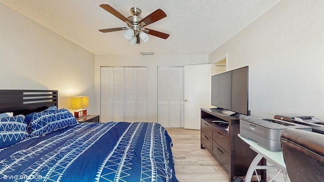 8912 Thumbwood Cir Unit C, Boynton Beach, FL 33436 - bedroom featuring light wood-style flooring, multiple closets, a ceiling fan, and a textured ceiling
