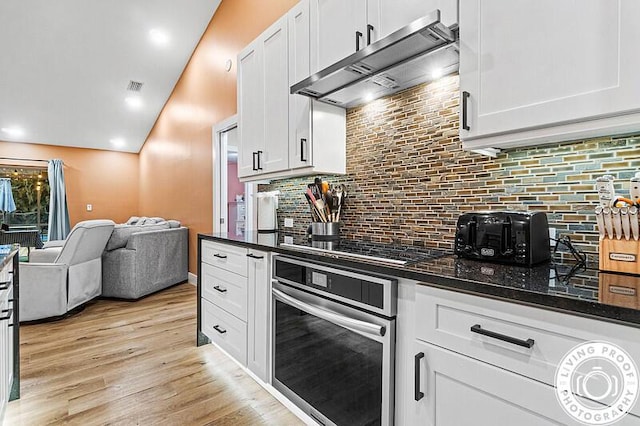 4038 Calamondin Blvd, The Acreage, FL 33470 - kitchen featuring oven, under cabinet range hood, white cabinets, open floor plan, and lofted ceiling