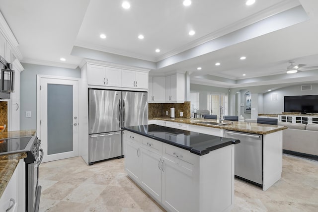 1948 Coco Palm Pl, Lauderdale By The Sea, FL 33062 - kitchen featuring appliances with stainless steel finishes, a sink, a tray ceiling, arched walkways, and a center island