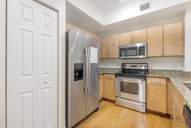 1801 N Flagler Dr Unit 107, West Palm Beach, FL 33407 - kitchen with appliances with stainless steel finishes, light wood-style flooring, and light stone countertops
