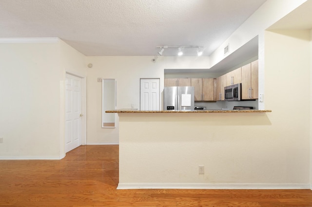 1801 N Flagler Dr Unit 107, West Palm Beach, FL 33407 - kitchen featuring stainless steel appliances, a peninsula, light stone counters, light wood finished floors, and a textured ceiling