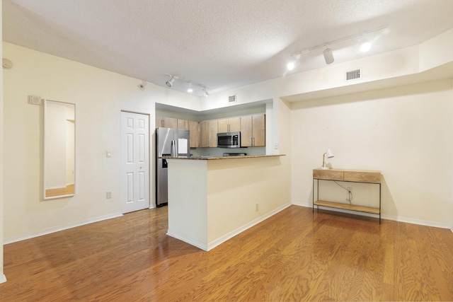 1801 N Flagler Dr Unit 107, West Palm Beach, FL 33407 - kitchen featuring appliances with stainless steel finishes, rail lighting, a peninsula, wood finished floors, and a textured ceiling