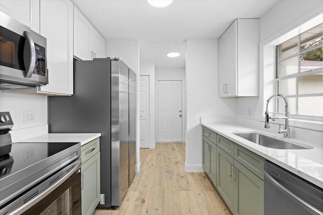 6681 4th St, Jupiter, FL 33458 - kitchen with appliances with stainless steel finishes, green cabinets, a sink, light wood-style flooring, and a textured ceiling