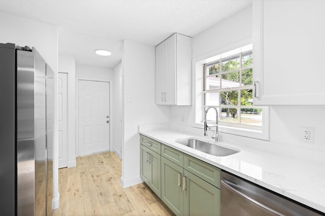 6681 4th St, Jupiter, FL 33458 - kitchen with green cabinetry, appliances with stainless steel finishes, a sink, light wood-style flooring, and a textured ceiling