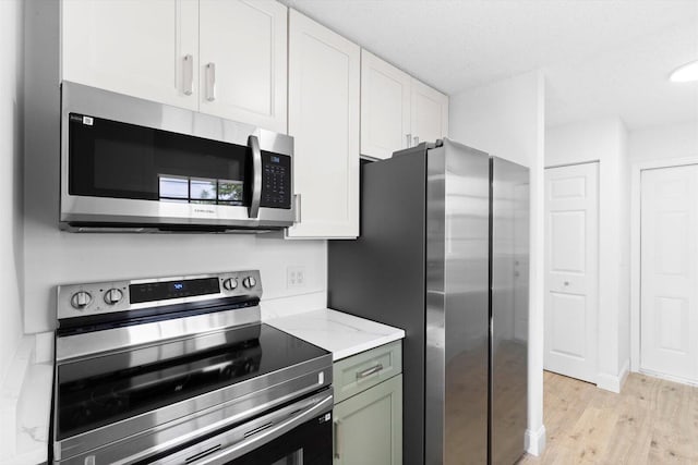 6681 4th St, Jupiter, FL 33458 - kitchen featuring appliances with stainless steel finishes, light wood-style flooring, white cabinets, and light stone counters