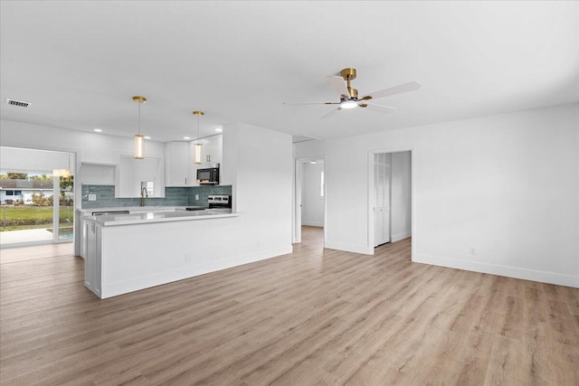 533 Riverside Dr, Palm Beach Gardens, FL 33410 - kitchen featuring black microwave, range with electric stovetop, light countertops, white cabinetry, and decorative backsplash