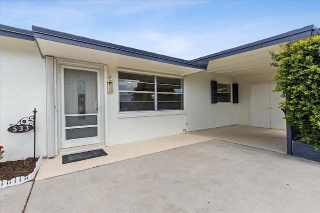 533 Riverside Dr, Palm Beach Gardens, FL 33410 - view of exterior entry featuring a carport, a patio, and stucco siding