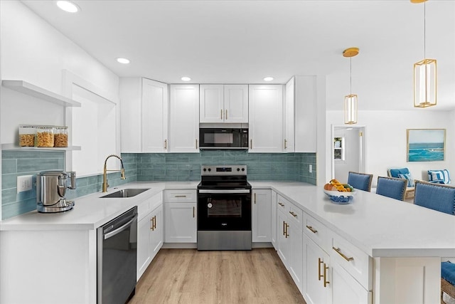 533 Riverside Dr, Palm Beach Gardens, FL 33410 - kitchen featuring appliances with stainless steel finishes, a peninsula, light countertops, light wood-style flooring, and white cabinetry