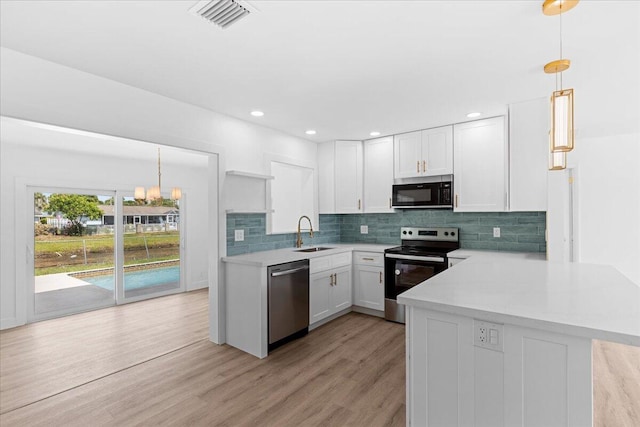 533 Riverside Dr, Palm Beach Gardens, FL 33410 - kitchen featuring appliances with stainless steel finishes, a peninsula, light countertops, white cabinets, and decorative backsplash