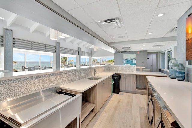 4740 S Ocean Blvd Unit 202, Highland Beach, FL 33487 - kitchen featuring modern cabinets, light countertops, a sink, light wood-style flooring, and backsplash