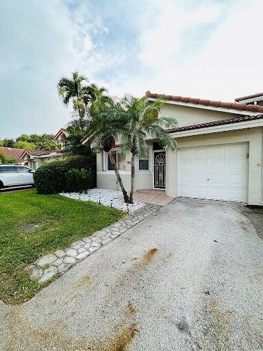 7624 Pinewalk Dr S Unit 147, Margate, FL 33063 - view of front of property with an attached garage, driveway, a front yard, and stucco siding