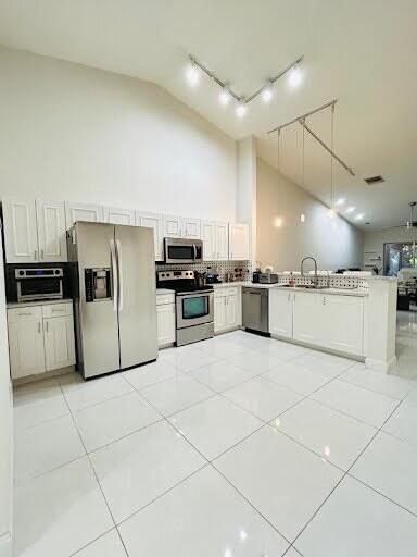 7624 Pinewalk Dr S Unit 147, Margate, FL 33063 - kitchen featuring appliances with stainless steel finishes, high vaulted ceiling, track lighting, a peninsula, and light tile patterned floors