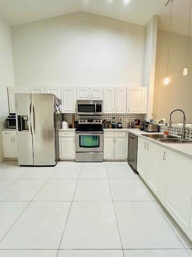 7624 Pinewalk Dr S Unit 147, Margate, FL 33063 - kitchen featuring appliances with stainless steel finishes, high vaulted ceiling, decorative backsplash, light countertops, and light tile patterned flooring