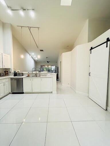 7624 Pinewalk Dr S Unit 147, Margate, FL 33063 - kitchen featuring stainless steel dishwasher, a barn door, track lighting, light tile patterned flooring, and vaulted ceiling