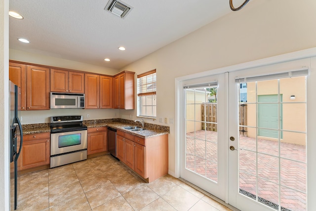 128 W Thatch Palm Cir, Jupiter, FL 33458 - kitchen with stainless steel appliances, a sink, dark stone countertops, recessed lighting, and brown cabinetry