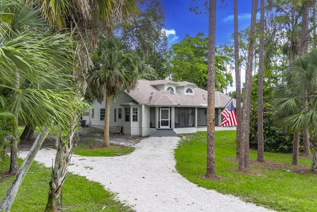 17069 81st Ln N, Loxahatchee, FL 33470 - view of front of property featuring gravel driveway, a sunroom, entry steps, a shingled roof, and a front lawn