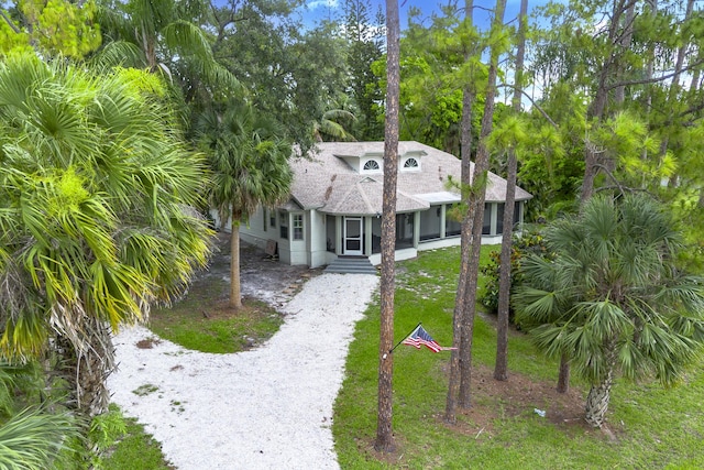 17069 81st Ln N, Loxahatchee, FL 33470 - view of front of property with gravel driveway, a sunroom, a shingled roof, a front lawn, and view of wooded area