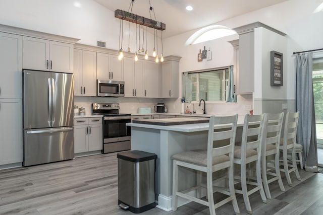 17069 81st Ln N, Loxahatchee, FL 33470 - kitchen with appliances with stainless steel finishes, a peninsula, a breakfast bar, light countertops, and light wood-type flooring