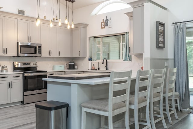 17069 81st Ln N, Loxahatchee, FL 33470 - kitchen featuring appliances with stainless steel finishes, light wood-style flooring, a breakfast bar, a peninsula, and light countertops