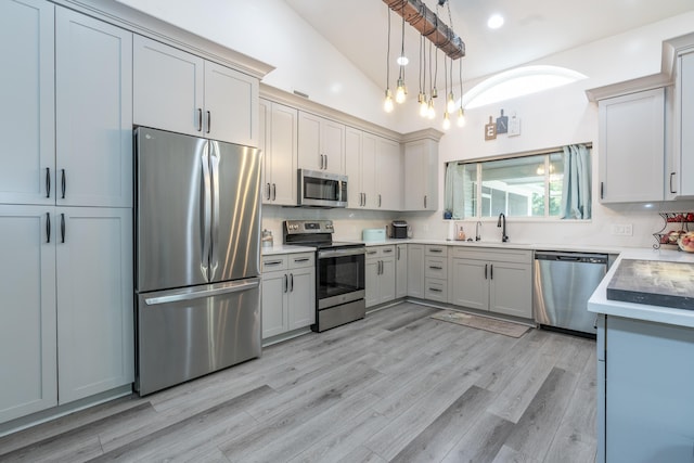 17069 81st Ln N, Loxahatchee, FL 33470 - kitchen featuring appliances with stainless steel finishes, a sink, pendant lighting, light wood-style flooring, and vaulted ceiling