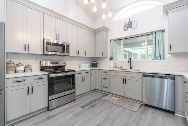 17069 81st Ln N, Loxahatchee, FL 33470 - kitchen featuring appliances with stainless steel finishes, a sink, light wood finished floors, light countertops, and pendant lighting