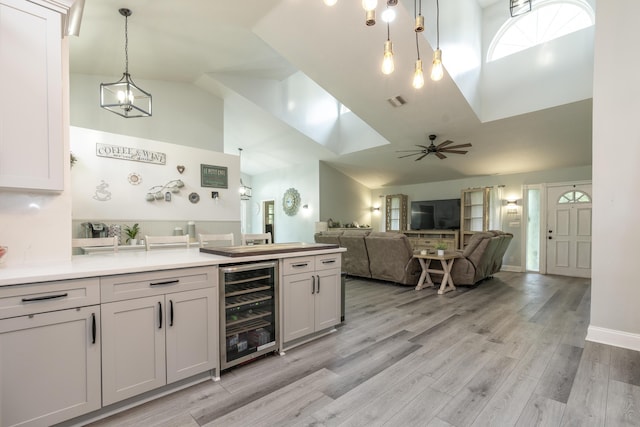 17069 81st Ln N, Loxahatchee, FL 33470 - kitchen with beverage cooler, high vaulted ceiling, ceiling fan, hanging light fixtures, and light wood finished floors