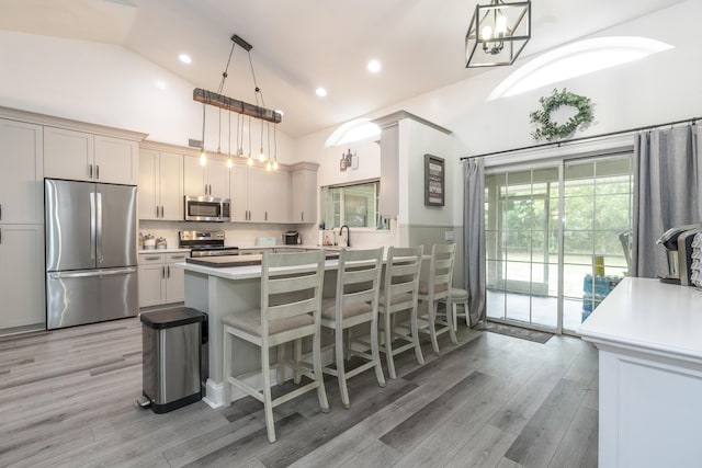 17069 81st Ln N, Loxahatchee, FL 33470 - kitchen with appliances with stainless steel finishes, light countertops, light wood finished floors, a sink, and a kitchen breakfast bar
