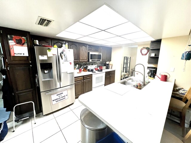 125 Capri Ave, Sebastian, FL 32958 - kitchen with appliances with stainless steel finishes, a sink, a peninsula, a kitchen breakfast bar, and light tile patterned floors