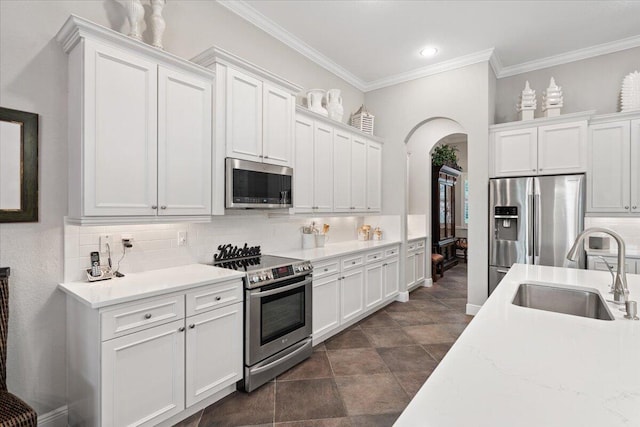 9926 SW Nuova Way, Port Saint Lucie, FL 34986 - kitchen featuring stainless steel appliances, a sink, arched walkways, decorative backsplash, and ornamental molding