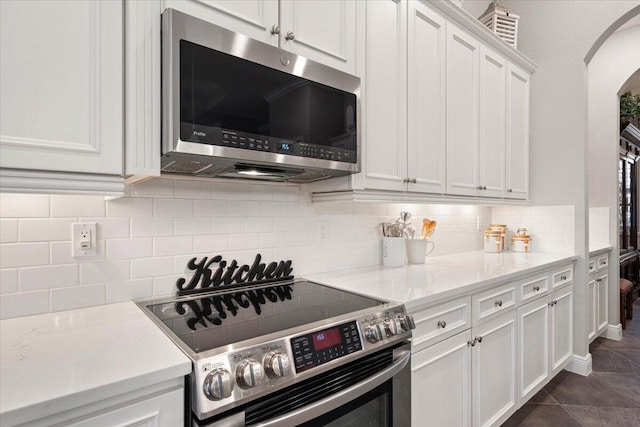 9926 SW Nuova Way, Port Saint Lucie, FL 34986 - kitchen featuring appliances with stainless steel finishes, arched walkways, white cabinetry, and tasteful backsplash