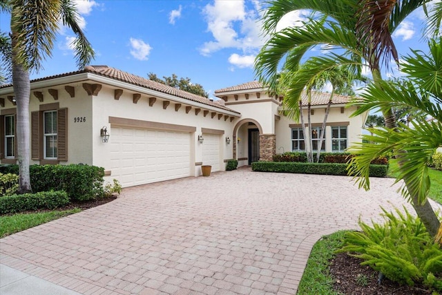 9926 SW Nuova Way, Port Saint Lucie, FL 34986 - mediterranean / spanish house with stucco siding, an attached garage, decorative driveway, and a tiled roof