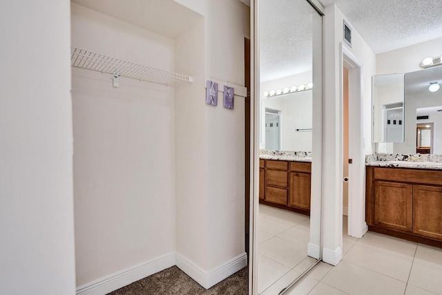 973 Springdale Cir Unit 97-C, Palm Springs, FL 33461 - full bath featuring vanity, baseboards, tile patterned floors, a spacious closet, and a textured ceiling