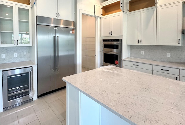 10705 Stellar Cir Unit 56, Palm Beach Gardens, FL 33412 - kitchen featuring appliances with stainless steel finishes, beverage cooler, backsplash, and white cabinets